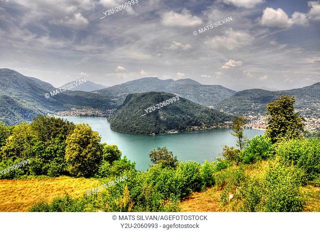 Alpine lake on the border with mountain and trees and grey sky in Ticino, Lombardy, Italy, Switzerland