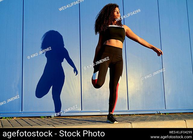 Sportswoman stretching leg on footpath