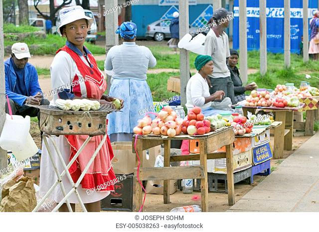 Black Zulu women in brightly colored clothing sell vegetables and produce as street vendors in Zulu village, Zululand, South Africa