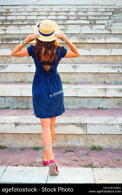 Beautiful girl on the steps in a blue dress and hat