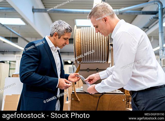 Two businessmen examining product in a factory