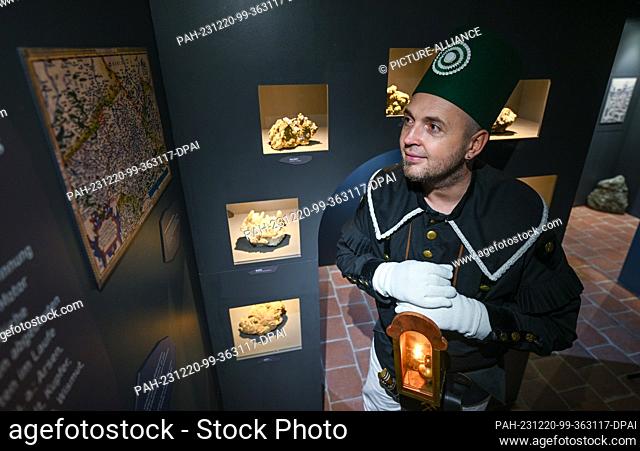 20 December 2023, Saxony, Drebach: In a festive miner's outfit, Christian Mädler stands in front of a presentation of minerals in the new mining labyrinth at...