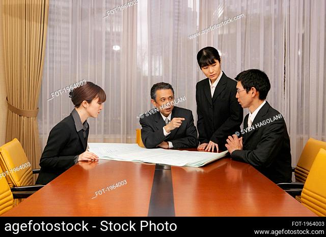 Business people discussing blueprints in office conference room