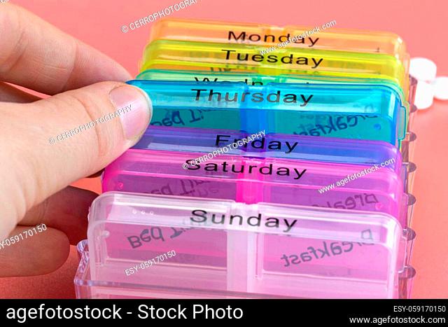 Pill box reminder, hand taking medicine daily pills in colorful box on pink background, elderly, senior, business, health
