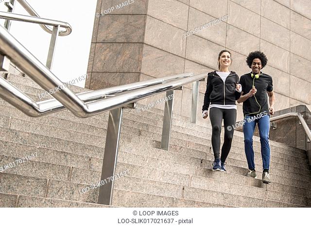 A young couple limbering up before a jog along the South Bank in London