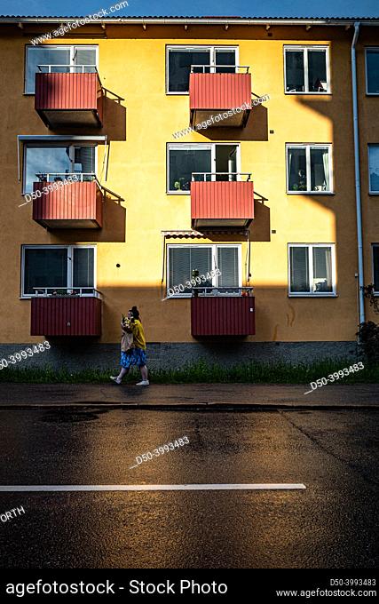 Stockholm, Sweden woman walks past an illuminated building at sunset in the Hagerstensensasen district