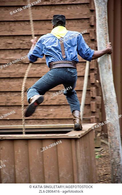 African American man with yellow bandana and suspenders about to jump with ropes inside a well