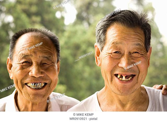 Portrait of two men with bad teeth smiling outdoors
