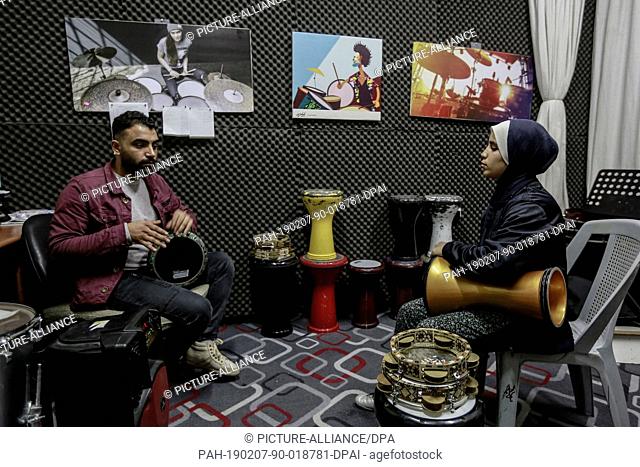 06 February 2019, Palestinian Territories, Gaza City: A Palestinian music teacher teaches a student how to play on a drum during a music class at the Edward...