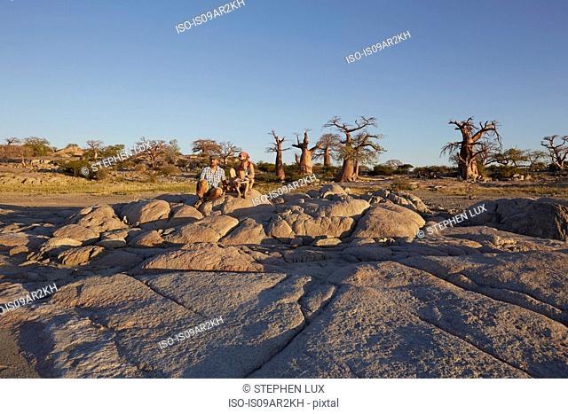 Family sitting on rocks, looking at view, Gweta, makgadikgadi, Botswana