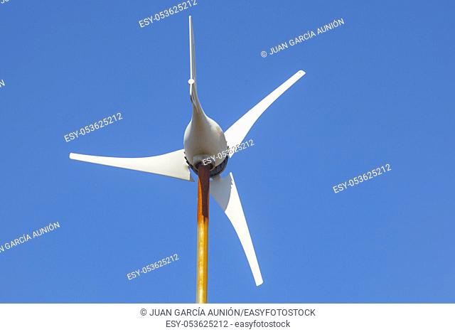 Domestic Wind Turbine mounted over metalic pole. Blue sky background