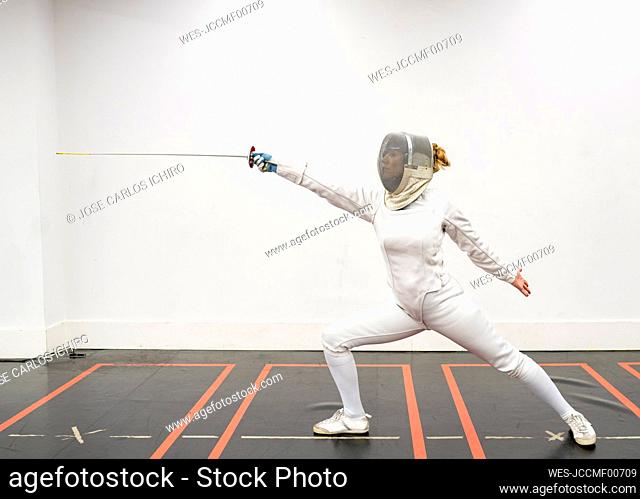 Woman¶ÿin fencing outfit practicing at gym