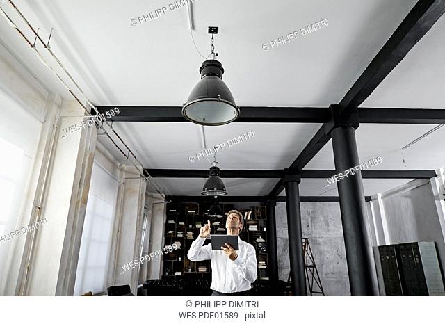 Mature man using digital tablet in loft flat