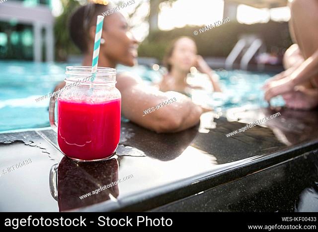 Fresh juice in mason jar with friends swimming at resort