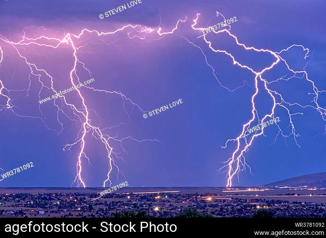 Lightning bolts striking Prescott area in the distance with the town of Chino Valley just north of Prescott Town in the foreground, Arizona