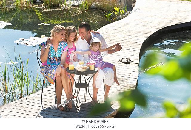 Austria, Salzburg County, Family having breakfast on bridge over pond