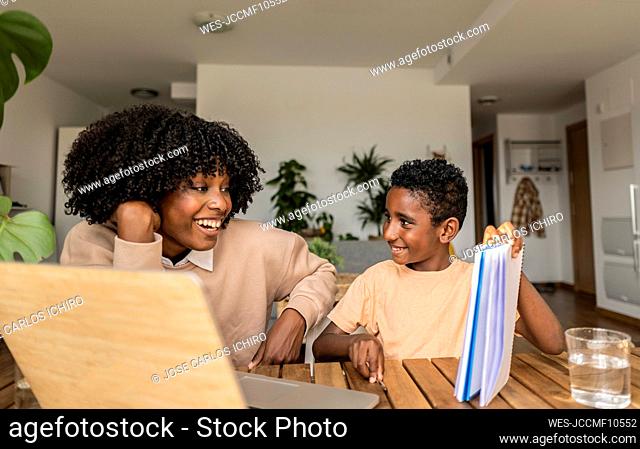 Happy son showing homework to mother at home