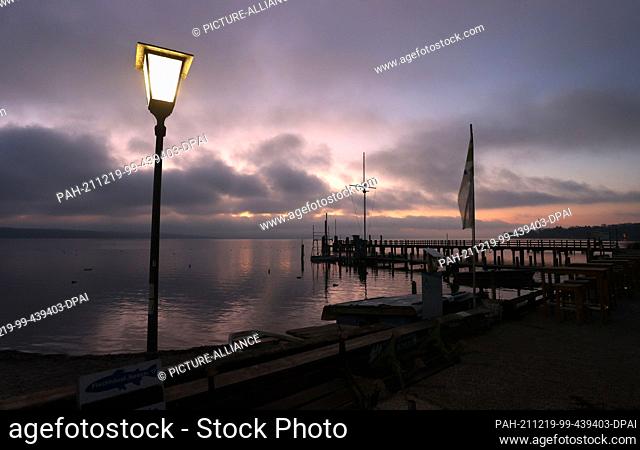 19 December 2021, Bavaria, Utting: The sky turns red shortly before sunrise behind a jetty at the Ammersee. Photo: Karl-Josef Hildenbrand/dpa