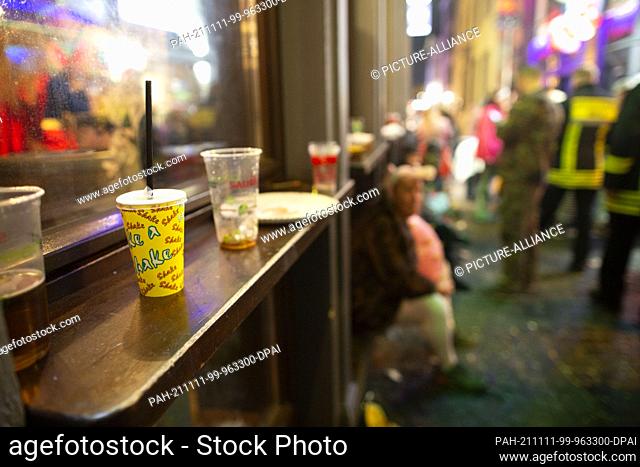 11 November 2021, North Rhine-Westphalia, Cologne: Drinking cups stand on a ledge at a local window. Carnivalists celebrate in the streets of Cologne's old town...