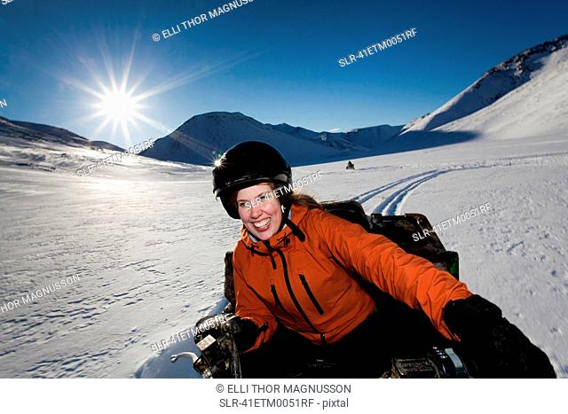 Woman driving snowmobile in snowy field