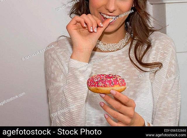 girl joyfully licks a finger and looks at a donut