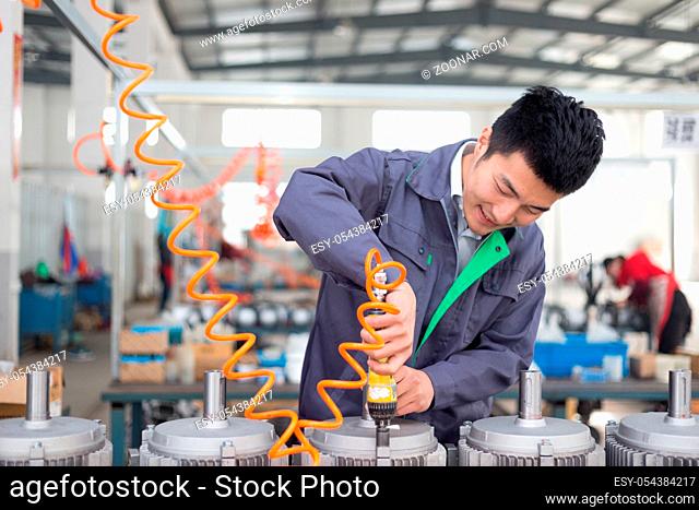 young chinese man works in motor manufacturing factory