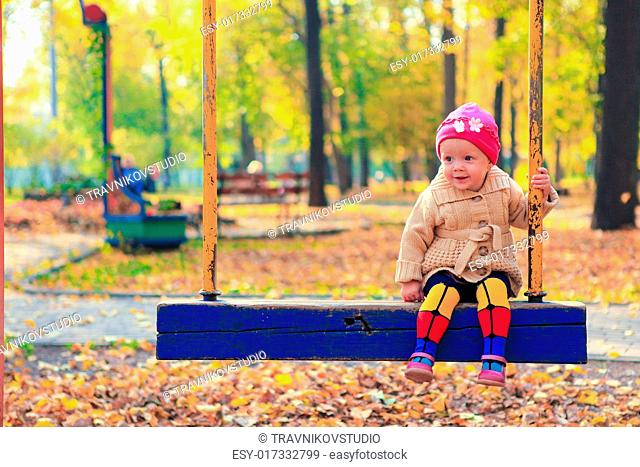 Little beautiful girl having fun on a swing in the autumn park