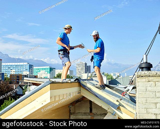 Men standing on rooftop of house at construction site
