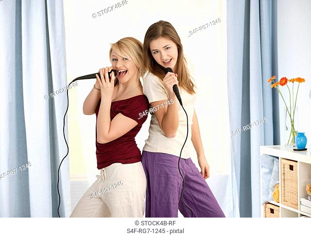 Two teenage girls singing in microphone