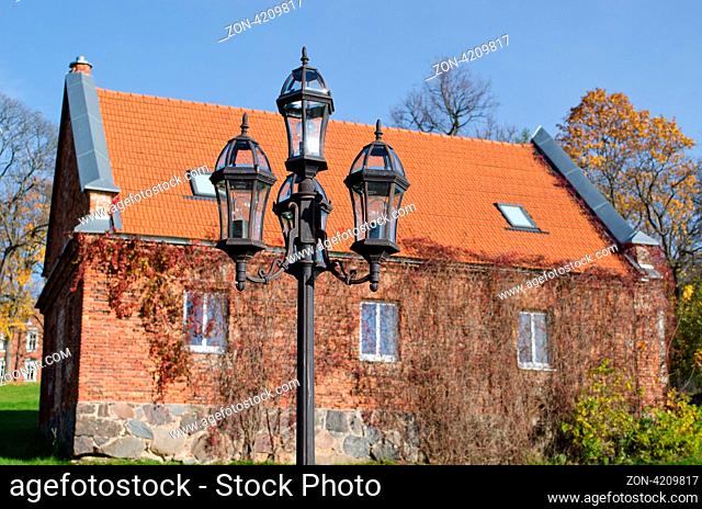 old retro steel lighting pole with four heads in park and renew restored house in background