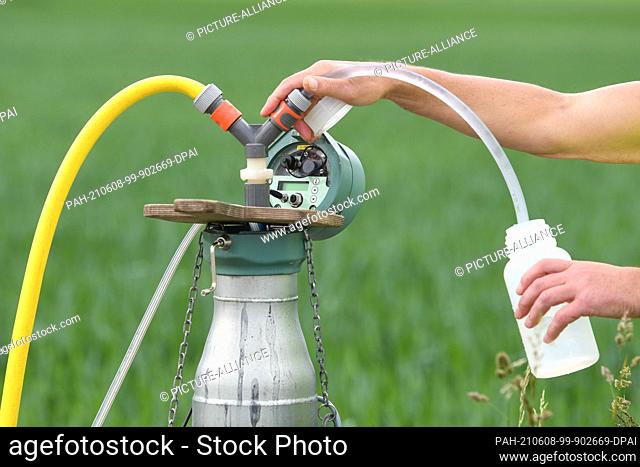07 June 2021, Bavaria, Moosinning: An employee of the Munich Water Management Office takes a water sample at a groundwater measuring point