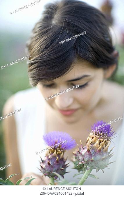 Young woman smelling thistle flowers