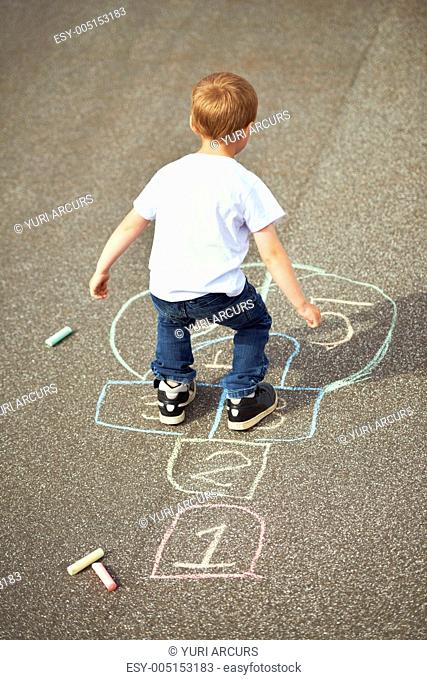 Rear view of a young boy playing hopscotch on the playground