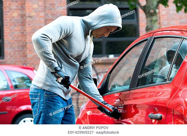 Thief In Hooded Jacket Using Crowbar To Open Car's Door