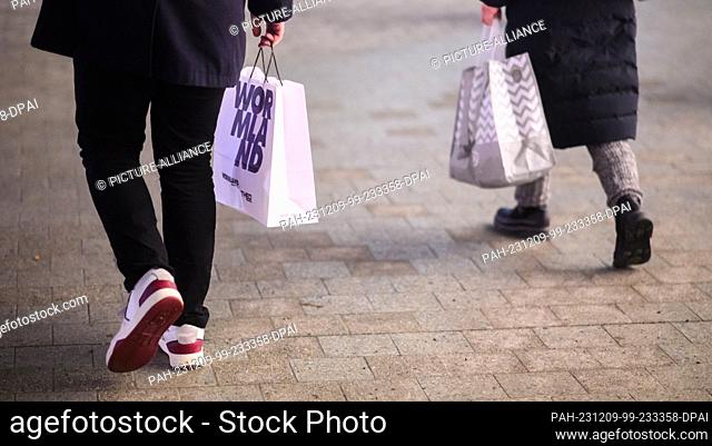 07 December 2023, Lower Saxony, Hanover: Two passers-by walk through the city center with shopping bags. Retailers in Lower Saxony can look back on a weak year...