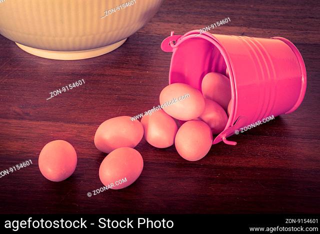 Easter eggs in a violet bucket on a wooden table