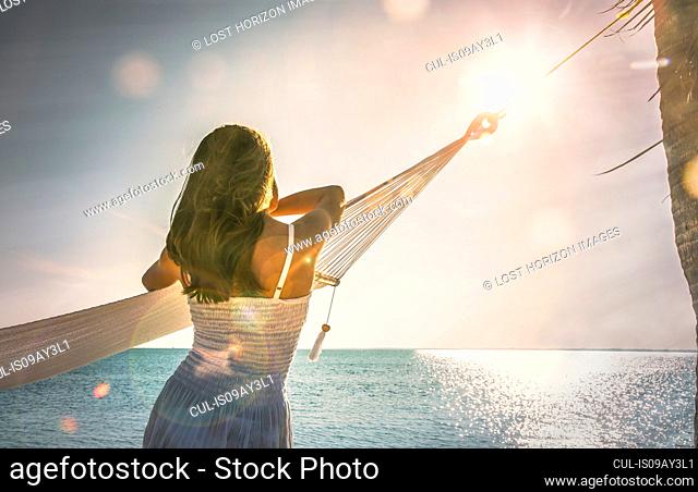 Young woman leaning against hammock watching sunset on Miami Beach, Florida, USA