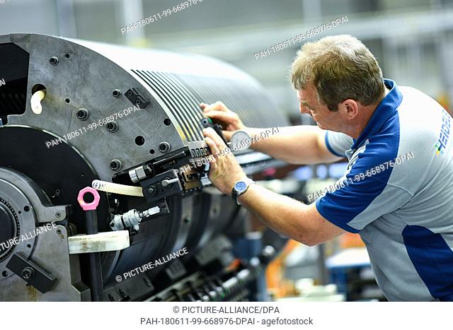 8 June 2018, Wiesloch, Germany: An employee stands at the storage drum of a large format printer at the factory of the Heidelberger Druckmaschinen AG