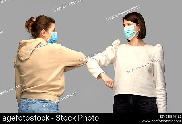women in masks making elbow bump greeting gesture