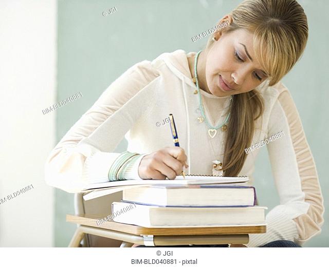 Young Hispanic woman writing at school desk