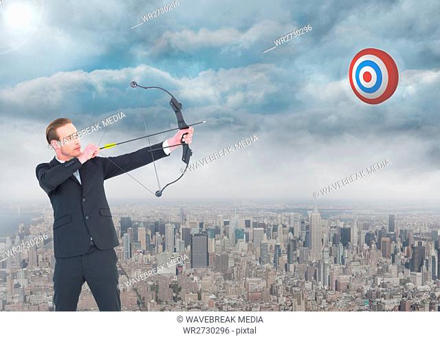 Businessman aiming with bow and arrow at target over cityscape
