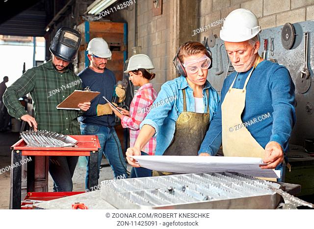 Gruppe Arbeiter im Betrieb für Metallbau planen zusammen die Produktion