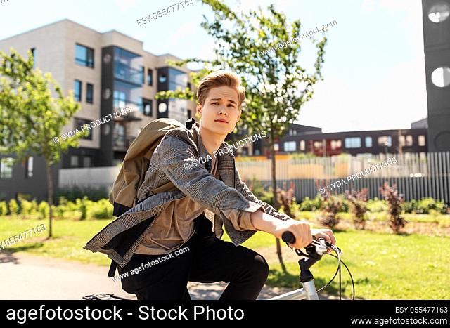 young man riding bicycle on city street