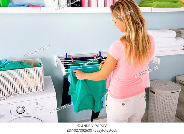 Woman Hanging Wet Clean Cloth To Dry On Clothes Line At Laundry Room