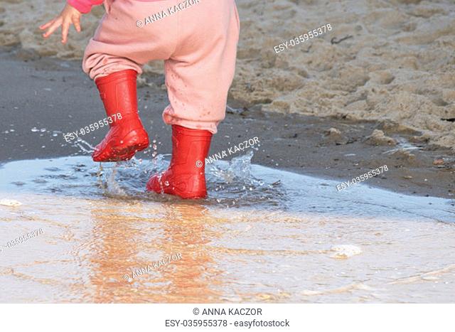 wellingtons in puddle.kid rubber boots in the sea background