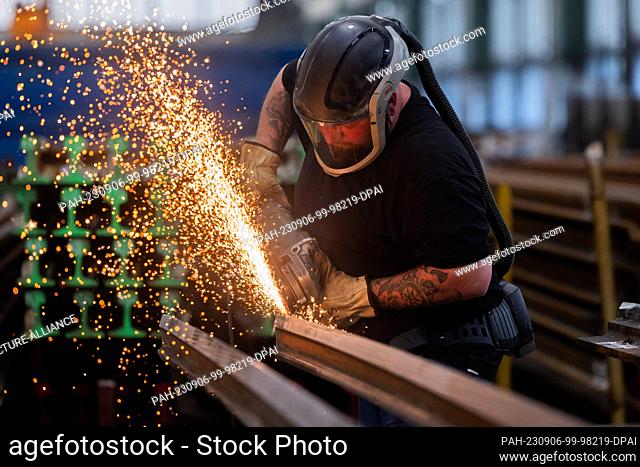 30 August 2023, North Rhine-Westphalia, Witten: A worker machines a switch tongue with an angle grinder at the plant for permanent way materials of Deutsche...