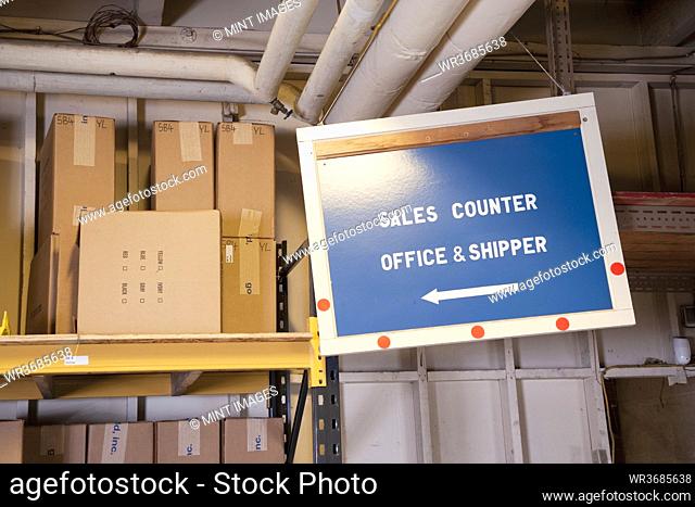 Sales counter sign and cardboard boxes on shelf in warehouse