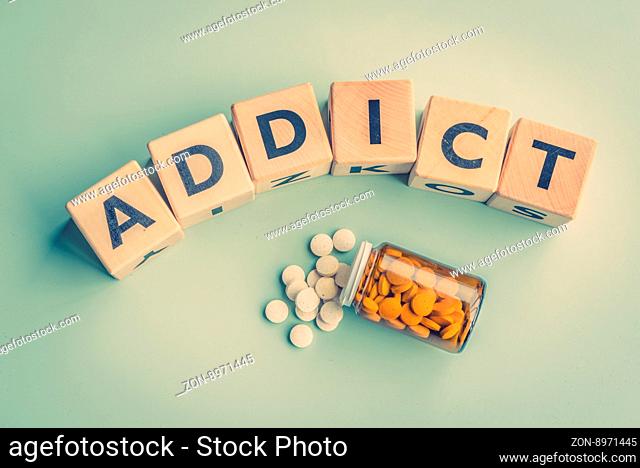The word addict on a table with pills