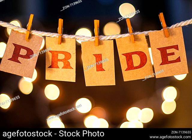 The word PRIDE printed on clothespin clipped cards in front of defocused glowing lights