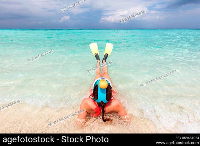 Woman wearing snorkeling mask and fins ready to snorkel in the ocean, Maldives. Clear turquoise water